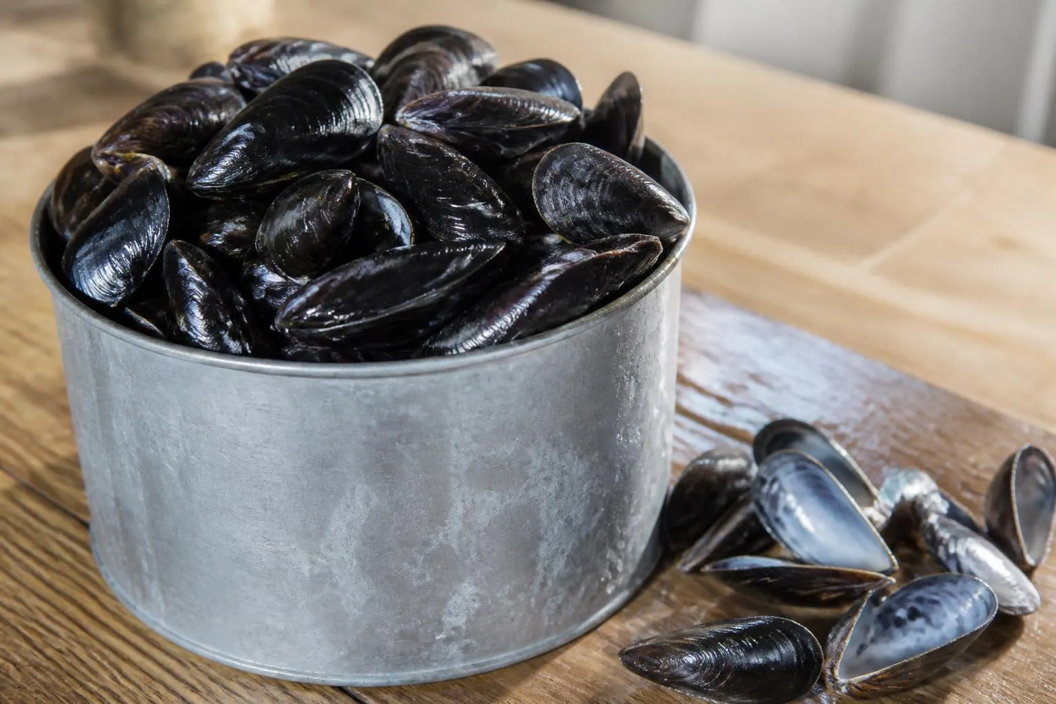 Moules noires entassées dans une mesure en zinc d'un litre posée sur un plan de travail